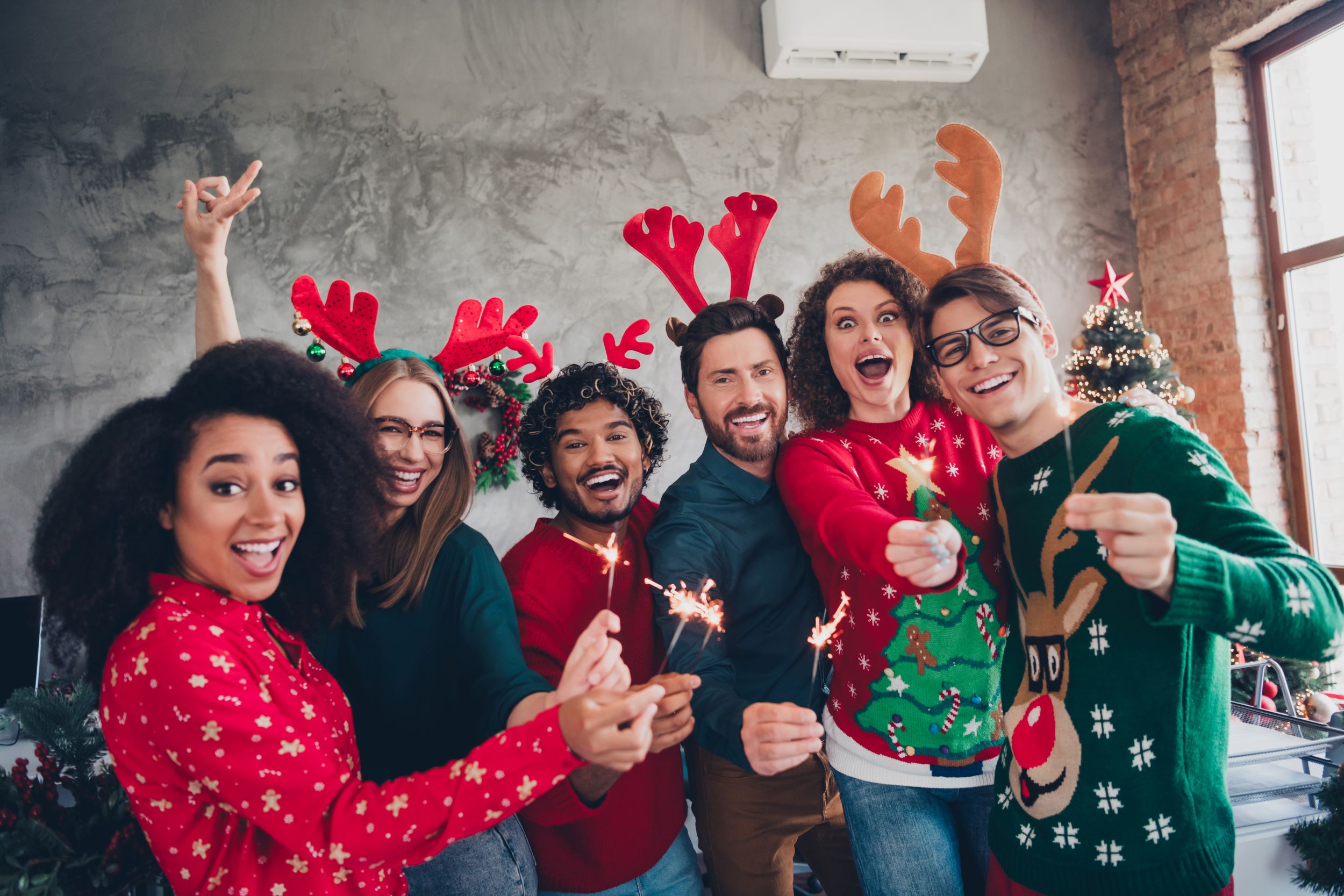 Business team in holiday sweaters holding sparklers